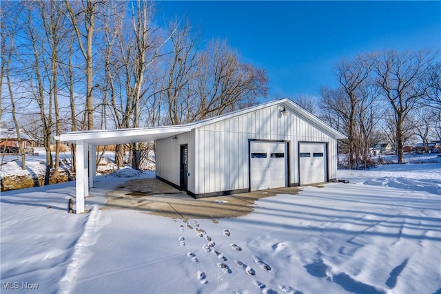 snow covered structure featuring a carport and a garage