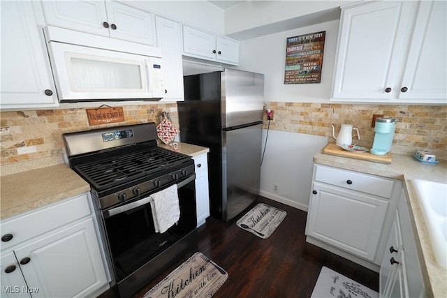 kitchen with freestanding refrigerator, white cabinets, light countertops, gas range, and white microwave