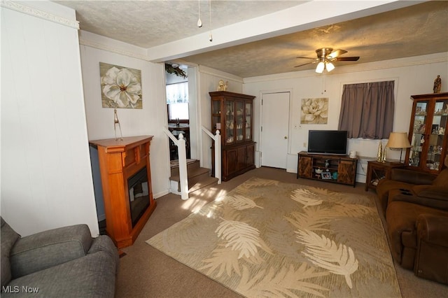 carpeted living room with ceiling fan, ornamental molding, and a textured ceiling