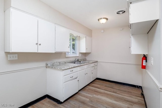 kitchen with white cabinetry, sink, and light hardwood / wood-style floors