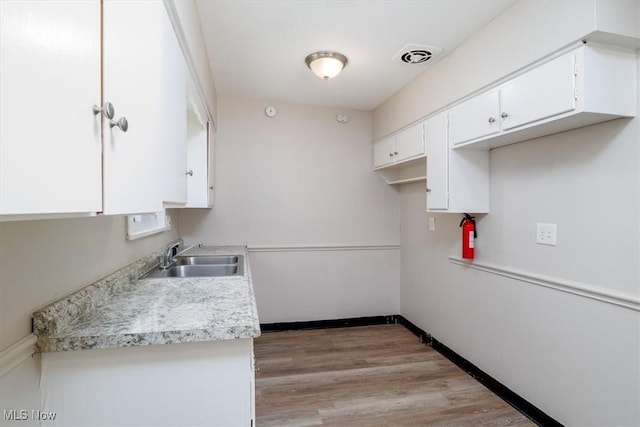 kitchen with white cabinetry, sink, and light hardwood / wood-style flooring