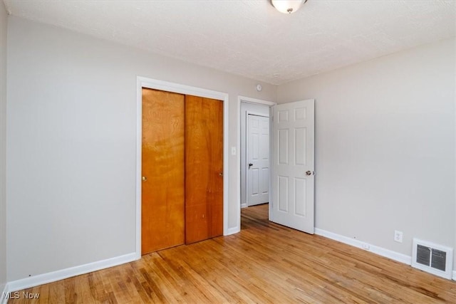 unfurnished bedroom with light hardwood / wood-style flooring and a closet