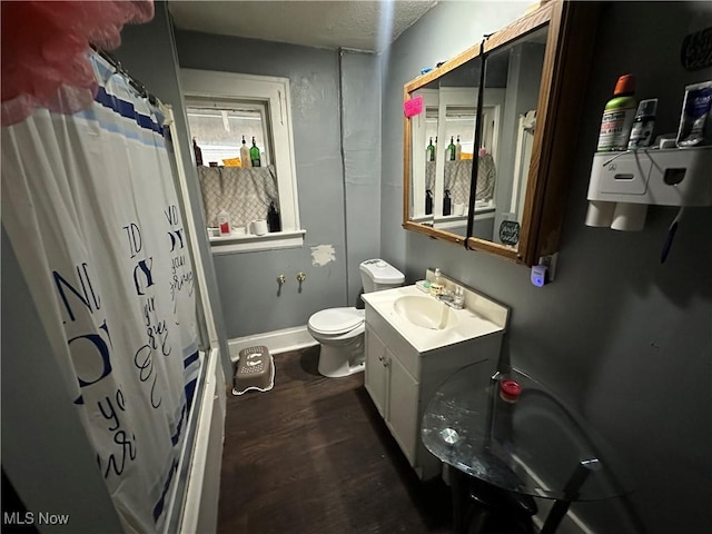 full bathroom with hardwood / wood-style flooring, shower / tub combo, vanity, a textured ceiling, and toilet