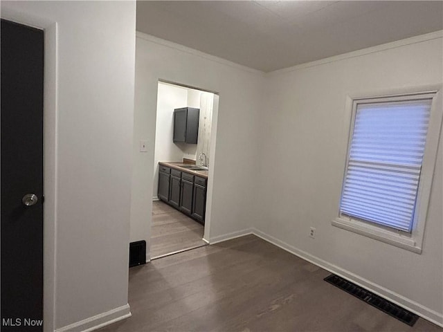 unfurnished room with crown molding, sink, and light hardwood / wood-style flooring