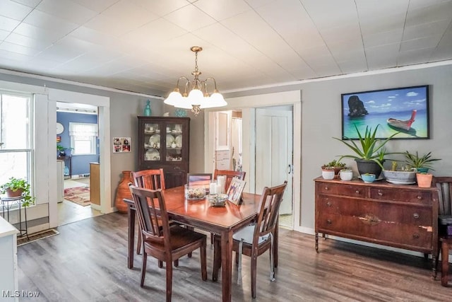 dining space with ornamental molding, hardwood / wood-style floors, and a notable chandelier