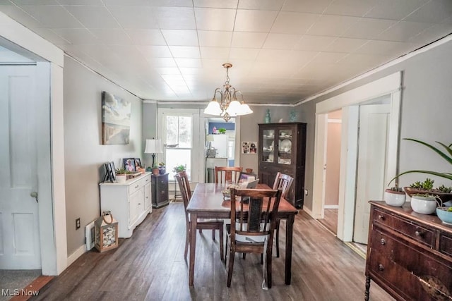 dining space featuring hardwood / wood-style flooring, crown molding, and a notable chandelier