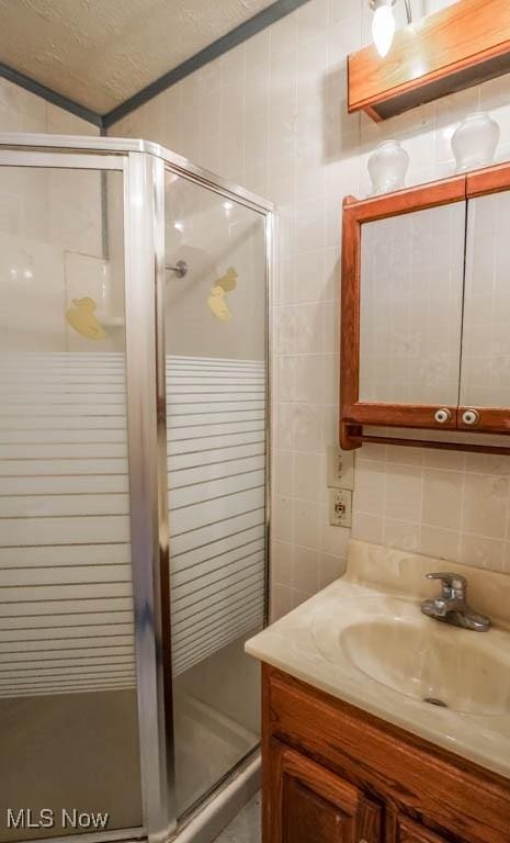 bathroom featuring vanity, a shower with shower door, decorative backsplash, and a textured ceiling