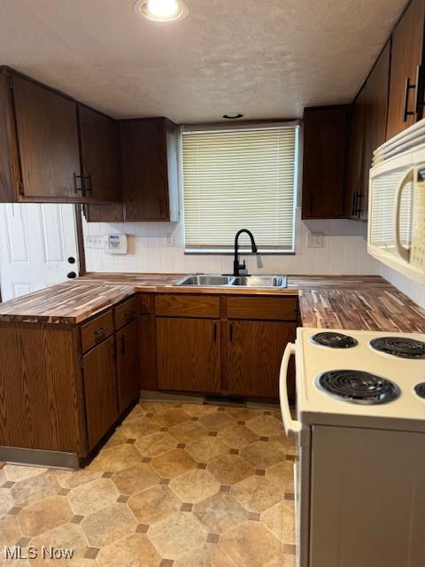 kitchen featuring dark brown cabinetry, sink, and white appliances