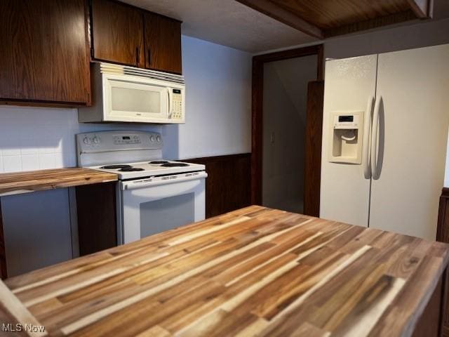 kitchen featuring white appliances, dark brown cabinetry, and butcher block counters