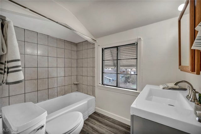 full bathroom with tiled shower / bath, wood-type flooring, lofted ceiling, vanity, and toilet