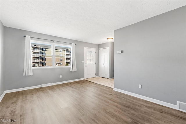 unfurnished room with a textured ceiling and light hardwood / wood-style flooring