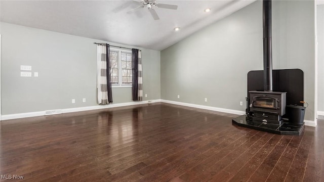 unfurnished living room featuring ceiling fan, lofted ceiling, dark hardwood / wood-style floors, and a wood stove