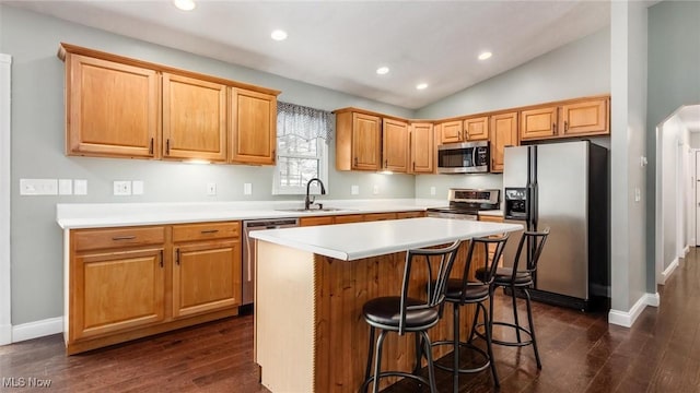 kitchen featuring lofted ceiling, sink, dark hardwood / wood-style flooring, a kitchen island, and stainless steel appliances