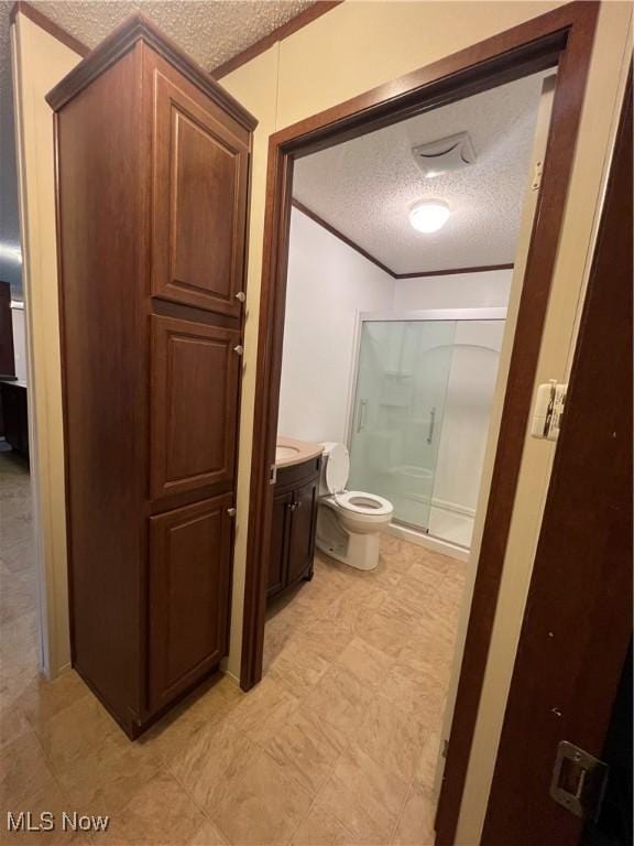 bathroom with vanity, toilet, a shower with door, crown molding, and a textured ceiling