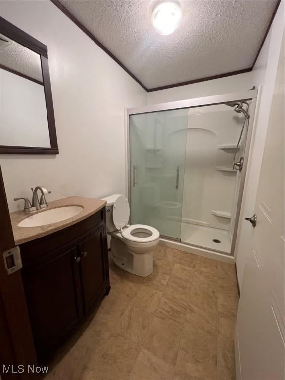 bathroom featuring toilet, a shower with shower door, a textured ceiling, ornamental molding, and vanity