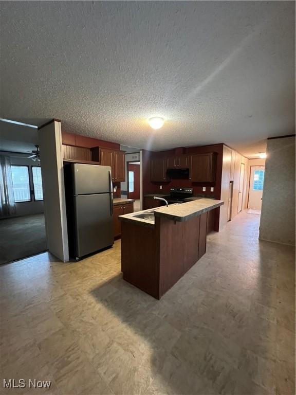 kitchen featuring a kitchen bar, sink, an island with sink, ceiling fan, and stainless steel appliances