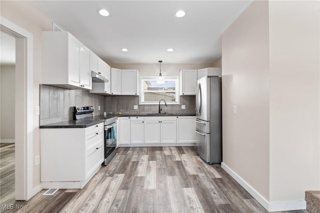 kitchen featuring appliances with stainless steel finishes, pendant lighting, tasteful backsplash, white cabinetry, and sink