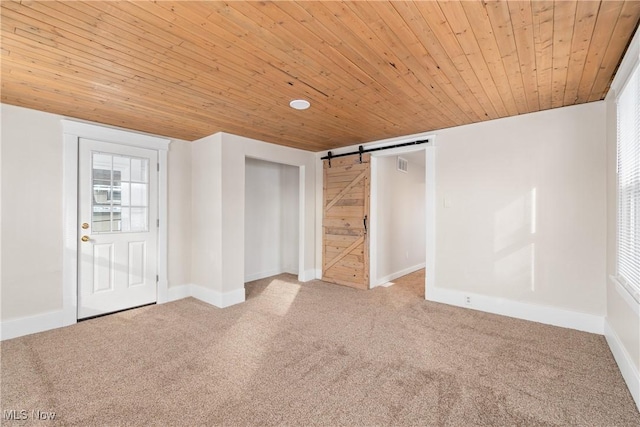 unfurnished bedroom featuring multiple windows, a barn door, wooden ceiling, and carpet