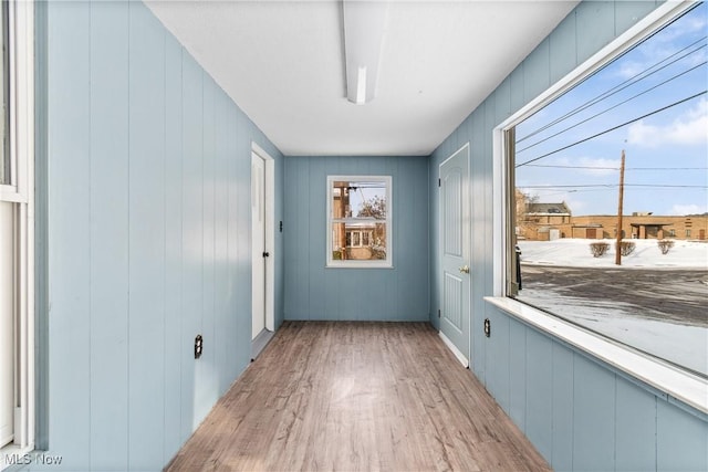 doorway with light hardwood / wood-style floors and wood walls