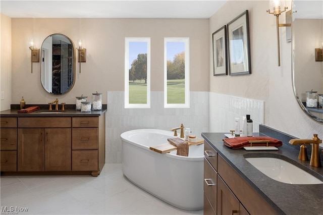 bathroom featuring tile patterned floors, vanity, tile walls, and a washtub