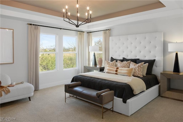 bedroom with light carpet, an inviting chandelier, and a tray ceiling