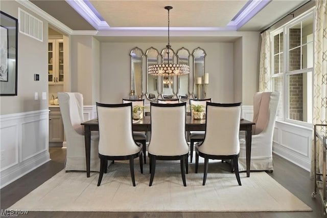 dining space featuring crown molding, wood-type flooring, a tray ceiling, and an inviting chandelier