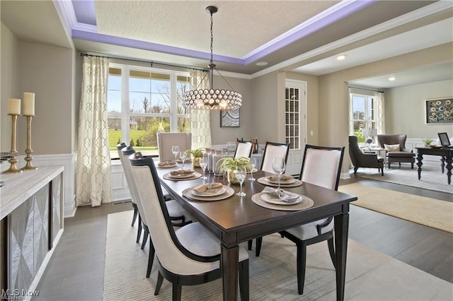 dining room with ornamental molding, a tray ceiling, and wood-type flooring