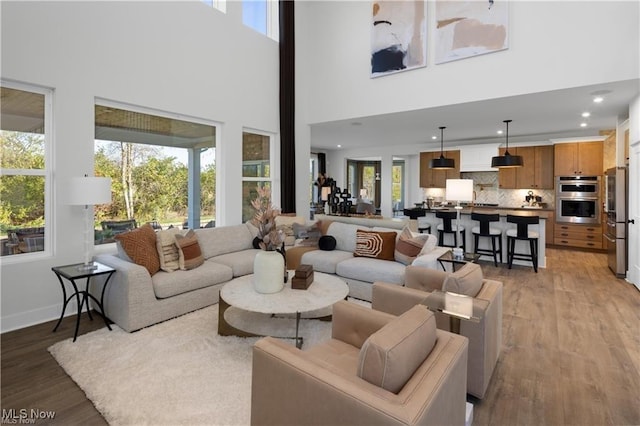 living room featuring a wealth of natural light, light wood-type flooring, and a high ceiling