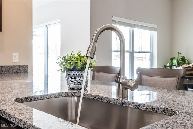 room details featuring light stone countertops and sink