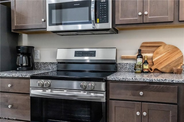 kitchen featuring appliances with stainless steel finishes, light stone countertops, and dark brown cabinets