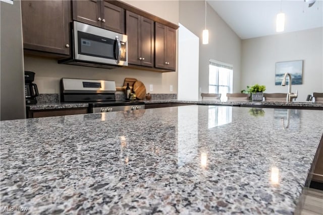 kitchen featuring sink, stone countertops, hanging light fixtures, dark brown cabinets, and appliances with stainless steel finishes