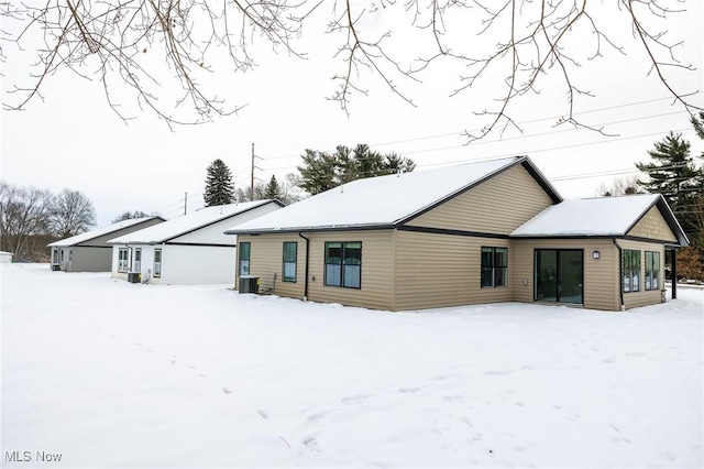 snow covered house featuring cooling unit