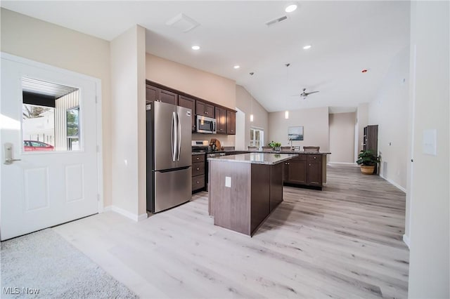 kitchen with decorative light fixtures, a center island, dark brown cabinets, light wood-type flooring, and appliances with stainless steel finishes