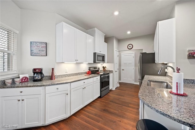 kitchen with sink, dark wood-type flooring, stainless steel appliances, light stone countertops, and white cabinets