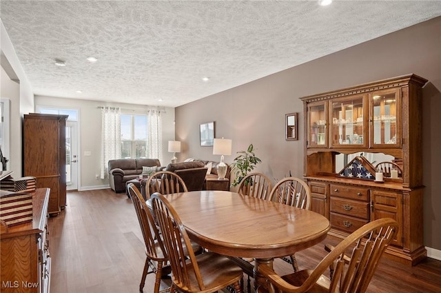 dining space with a textured ceiling and dark hardwood / wood-style flooring