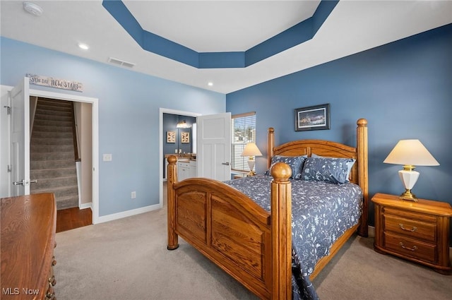 bedroom featuring a tray ceiling and light carpet