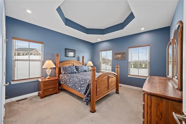 carpeted bedroom with a tray ceiling