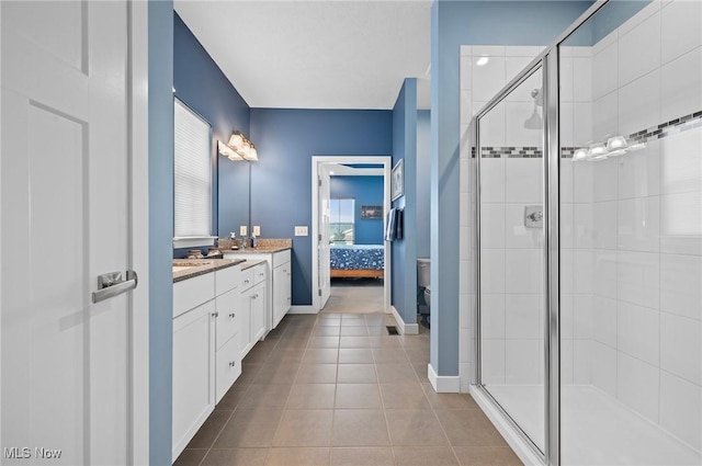 bathroom with a shower with door, vanity, tile patterned floors, and toilet