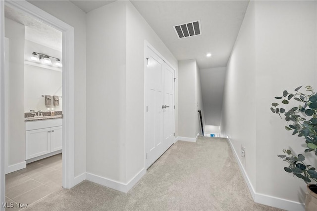 hallway with sink and light carpet