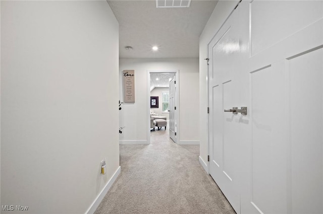 hall featuring light carpet and a textured ceiling