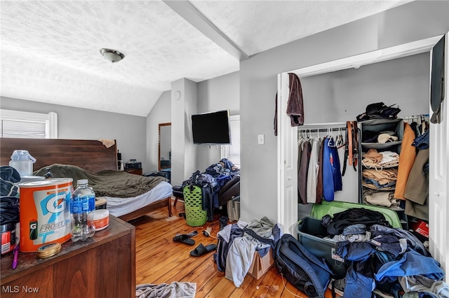 bedroom featuring hardwood / wood-style flooring, vaulted ceiling, a textured ceiling, and a closet