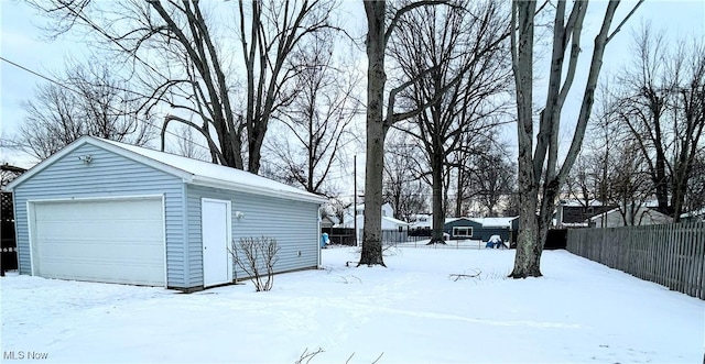 yard layered in snow featuring a garage and an outbuilding