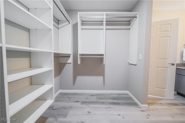 walk in closet with light hardwood / wood-style floors