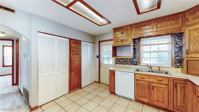 kitchen featuring white dishwasher, sink, decorative backsplash, and light tile patterned flooring