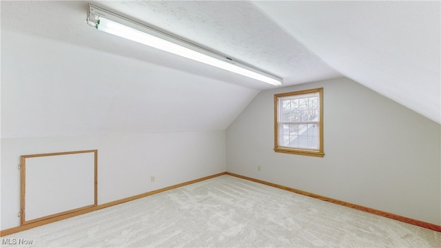 additional living space featuring light colored carpet and vaulted ceiling