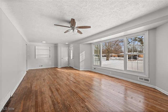 unfurnished living room featuring hardwood / wood-style floors, a textured ceiling, ceiling fan, and built in shelves