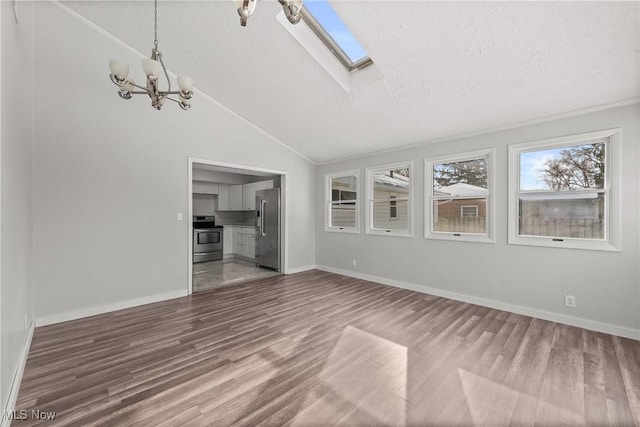 unfurnished living room featuring lofted ceiling with skylight, hardwood / wood-style floors, a textured ceiling, and an inviting chandelier