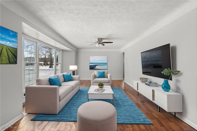 living room featuring ceiling fan, dark wood-type flooring, and a textured ceiling