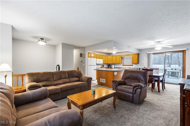 living room with light carpet, ceiling fan, and a textured ceiling