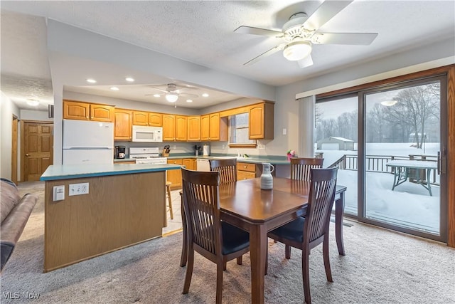 carpeted dining space with a textured ceiling and ceiling fan